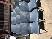 Set of 12 gray plastic outdoor chairs with metal legs arranged outdoors in sunlight.