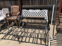 Black metal bench frame with decorative scrollwork, no cushions, 68 inches wide, in outdoor setting alongside other furniture.