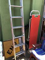 Photo of ladder leaning against green wall with yellow 'END' street sign and Gemini XL hand truck and dolly.