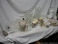 Wide view of all china and glass items on white cloth, showing floral china and various glass pieces