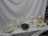 Full view of lot showing porcelain plates, cups, saucers, clear glassware including bowls and glasses, with a blue decorative porcelain bowl in center.