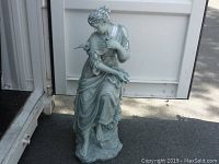 Full view of the statue showing the seated lady in flowing dress with bird on arm.