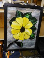 Full view of the framed leaded glass sunflower window showing yellow petals, green leaves, brown center, and wooden frame.