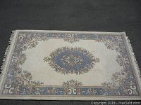 Full view of the rectangular carpet showing central floral medallion, border design, and overall color scheme