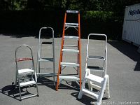 Front view showing all five stepladders lined up on pavement.