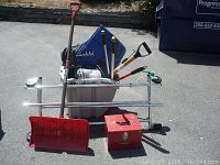 Overview of the lot including snow shovel, toolbox, garden rakes and tools in plastic container