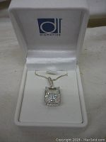 Sterling silver pendant with large rectangular clear stone and chain displayed in open white Diamonite box.