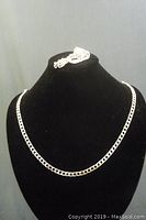 Photo showing the 21-inch marked sterling silver chain necklace displayed on a black jewelry bust with the bracelet coiled on top.