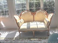 Front view of the round back upholstered settee with pillows, showing detailed wood carving and patterned fabric upholstery.