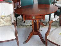 Full view of the round wood drop side table showing drawer, turned legs, and fold-down sides