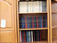 Photo of American Heritage hardcover book collection on wooden shelves near a staircase in a den