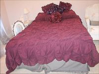 Full view of the made bed with dark red/maroon comforter and pillows