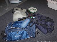 Photo showing assortment of items including blue Reebok duffel bag, gray Intex bag, Prince tennis racket, golf putter.