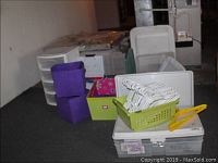 View of multiple plastic storage totes, drawer organizers, fabric storage cube, file boxes, and plastic clothes hangers.
