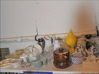 Photo of glassware including stemmed glasses, clear dishes, white and silver pitchers, and a brown ceramic container with lid.