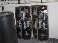 Four black rectangular mother of pearl chinoiserie panels showing the overall set, with detailed figures and textured inlay work. Panels hung vertically in basement area with visible scratches and wear.