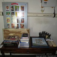 Overview of table with baseball card books, stamp books, framed stamp collection, menorah, and pens