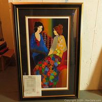 Full view of framed serigraph leaning against wall with paperwork placed in front.