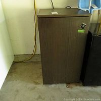 GE mini fridge with brown exterior, noted scratches on front and sides, placed against a wall with power cable