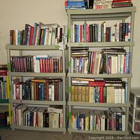 Two Keter plastic shelving units filled with books for size reference. Shelving unit on left has 4 shelves, 36x18x54 inches. Shelving unit on right has 5 shelves, 36x18x72 inches. Shelves made of light gray plastic with slight bowing visible on some shelves.