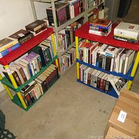 View of six plastic shelves filled with books on various topics, showing the general lot contents.