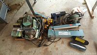 Overview of all items including soldering irons, heat guns, and heat sealer on garage floor.