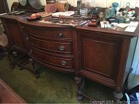Front side view of the wooden buffet showing curved drawers and cabinet door with ornate legs.