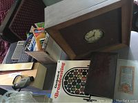 Wooden framed Motorola 59R1 radio with clock mounted, broadcasting book, litho block color printing guide, batteries, bookmarks, and calculators grouped on a table.