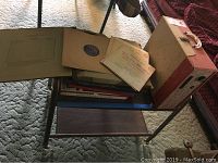 Photo showing metal rolling cart with wood shelves and vintage records placed on top and bottom shelf.