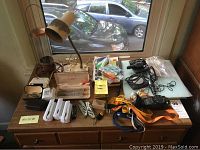 Wide shot of men's accessories assortment on wooden desk including outdoor timer, lighters, pens, sunglasses, and small tools