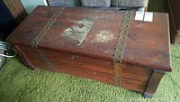 Top view of cedar chest showing heavy wear and original brass hardware straps with rivets.