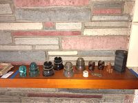Wide view of full lot including glass and ceramic lighting insulators and black industrial magnets lined up on wooden shelf.