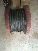 Steel cable wound on spool, showing full spool with cable looped around wooden red ends.