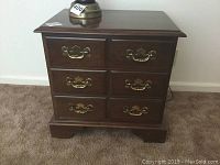 Front view of the small wooden chest showing three drawers with brass handles and minor surface wear.