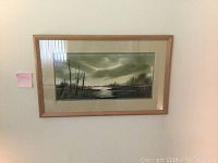 Horizontal landscape painting with trees and cloudy sky in light wood frame with matting.