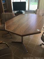 View of the octagonal top of the oak dining table showing wood grain and table base with four metal legs.