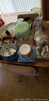 Overview of table with kitchen items including mixing bowls, serving ware, placemats, and utensils