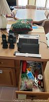 Wooden desk top with Panasonic cordless phone handsets and assorted office supplies in open drawer