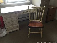 Full view of the white painted desk with floral drawer decoration next to the Hitchcock spindleback chair with wooden seat.