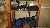 Shelf with multiple bags including duffle and rolling backpack, all in blue and black colors
