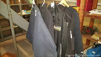 Photo showing dark colored Toyota employee jackets and fleece pullovers on hangers including Tundra and Toyota Racing Development logos.