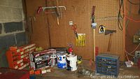 Wide view of workshop wall with hanging hand tools, hardware boxes, paint cans, and pegboard