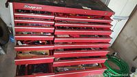 Snap-on red tool chest with multiple drawers open showing sockets, ratchets and hand tools