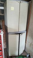 Two stacked beige plastic storage cabinets showing front closed doors with minor scuffs and marks.