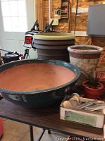 Photo showing two main flower pots and live succulent plant placed on the floor and table in a garage or shed setting.