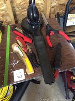 Overall view of Toro Power Sweep blower and multiple garden cutting tools including pruning saws and shears on table