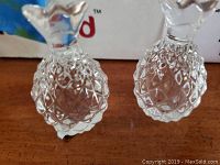 Pair of clear crystal pineapple-shaped salt and pepper shakers with faceted geometric texture on wooden surface