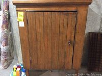 Front view of antique wooden food safe cabinet with paneled door.