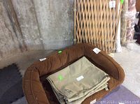 Orvis brown dog bed with tan crate covers inside and wooden dog gate in background