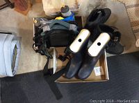 Black LL Bean women's rubber boots sitting in box with hiking boots and backpacks behind
